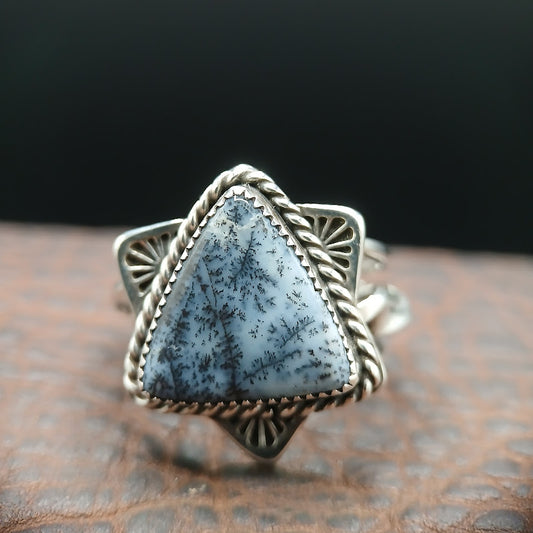 Dendritic opal sterling silver statement ring, front view on leather platform with dark background