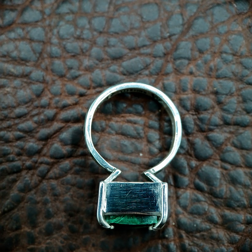 flat view of silver and green stone ring on dark leather