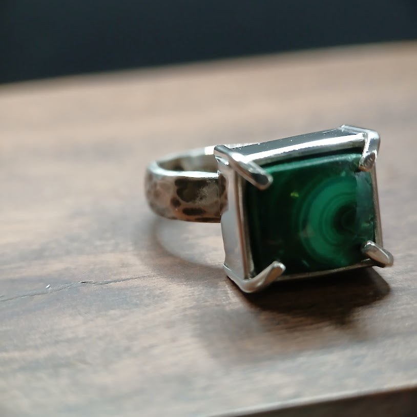 Silver ring with a green stone on a wooden surface