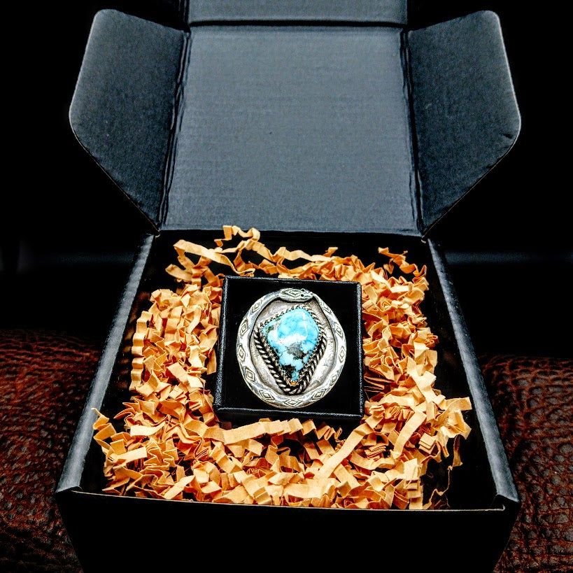 Jewelry box with decorative paper and a silver ring with a blue gemstone on a dark background