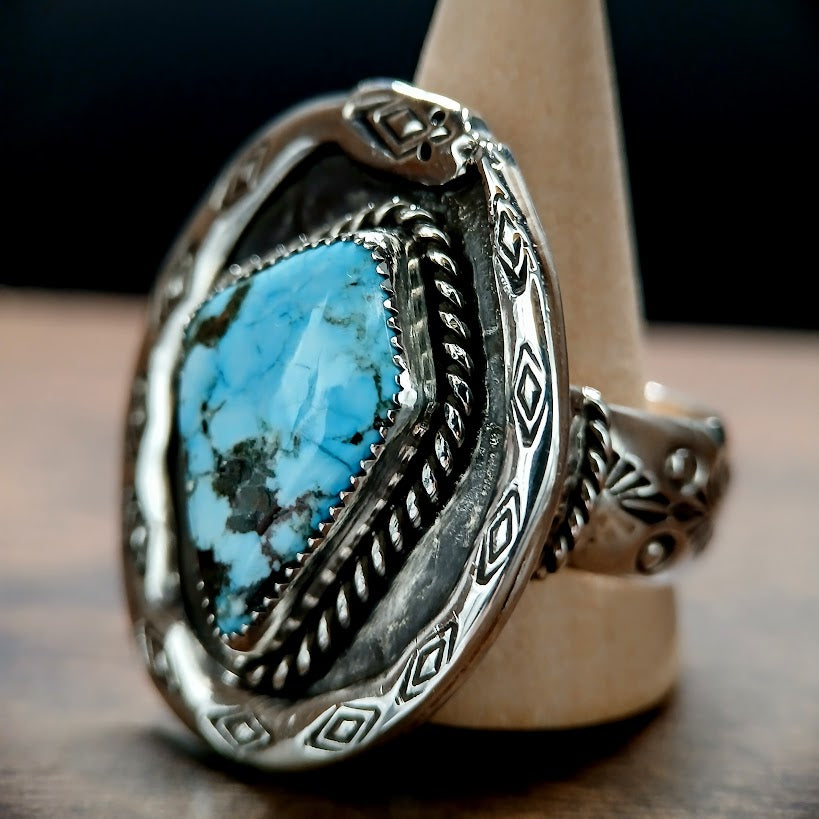 Silver ring with a blue stone on a wooden stand