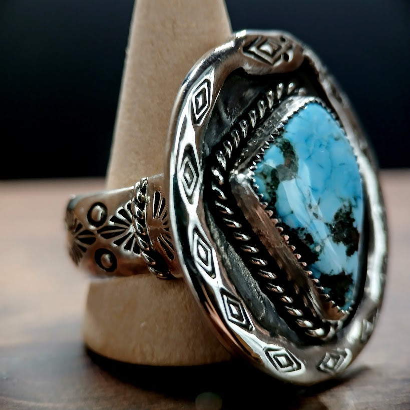 Silver ring with turquoise stone on a wooden stand