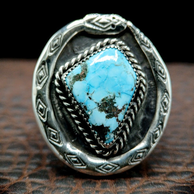 Silver ring with a turquoise stone on a textured surface