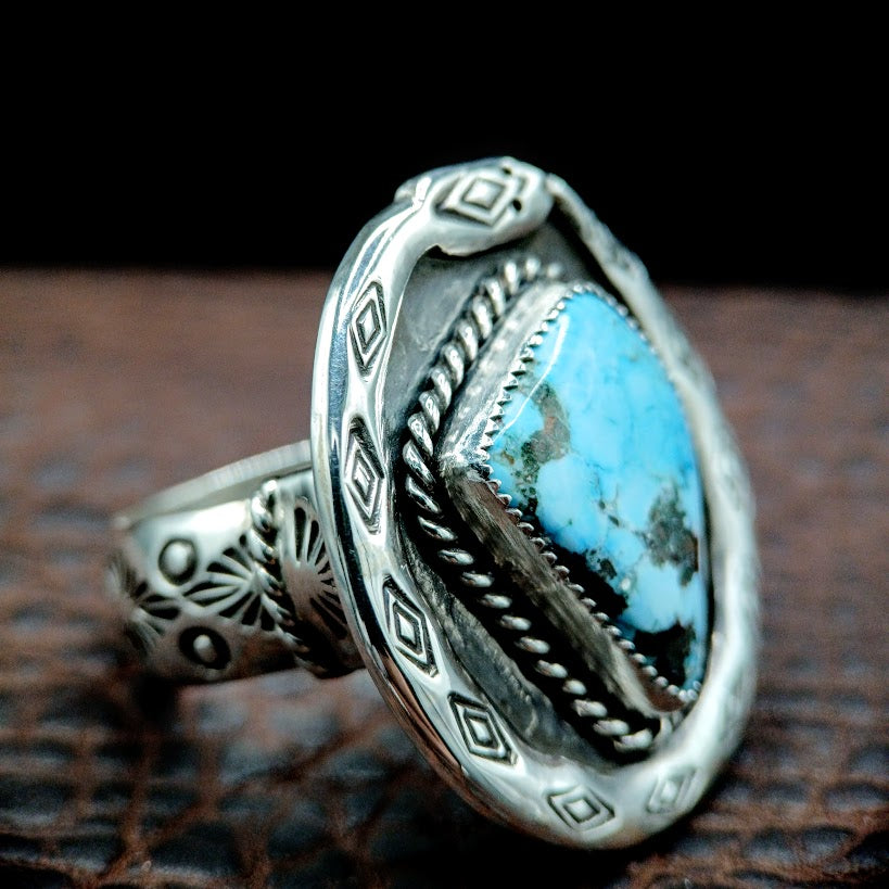 Silver ring with a blue stone on a textured surface