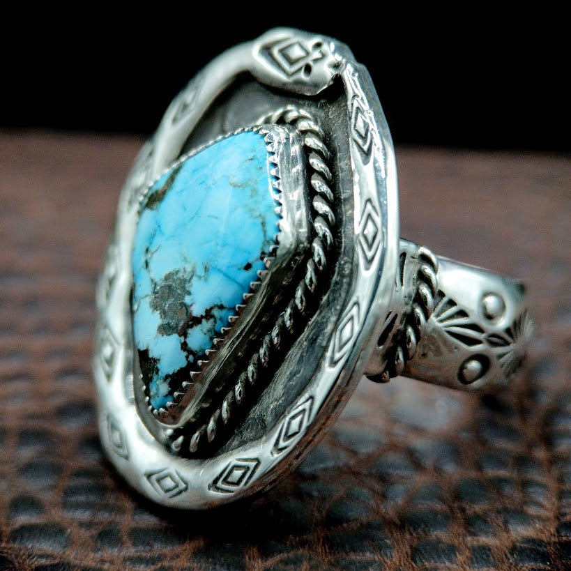 Silver ring with turquoise stone on a textured surface