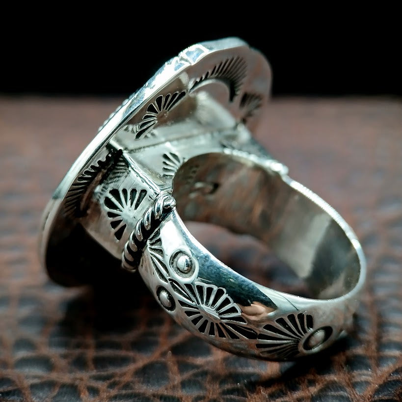 Silver ring with intricate designs on a textured surface