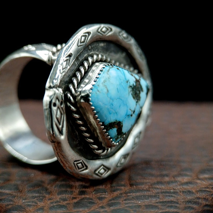 Silver ring with a turquoise stone on a brown leather surface