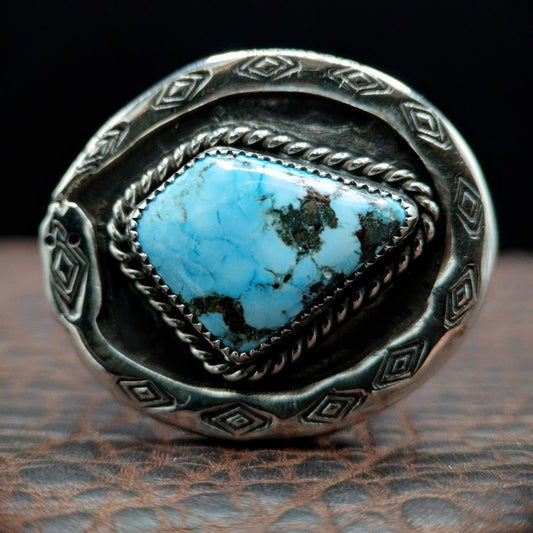 Silver ring with a turquoise stone on a textured surface