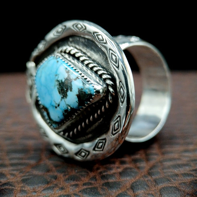Silver ring with turquoise stone on a textured surface