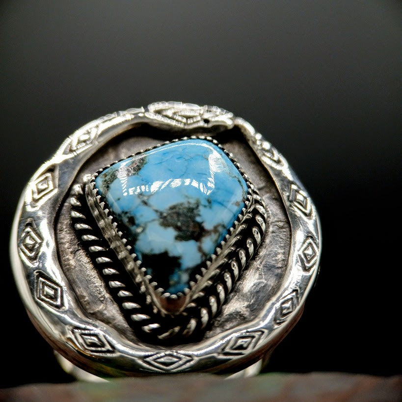 Silver ring with a turquoise stone on a dark background