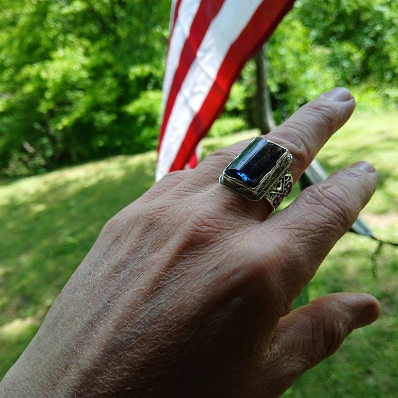 Hand wearing a ring with an American flag in the background