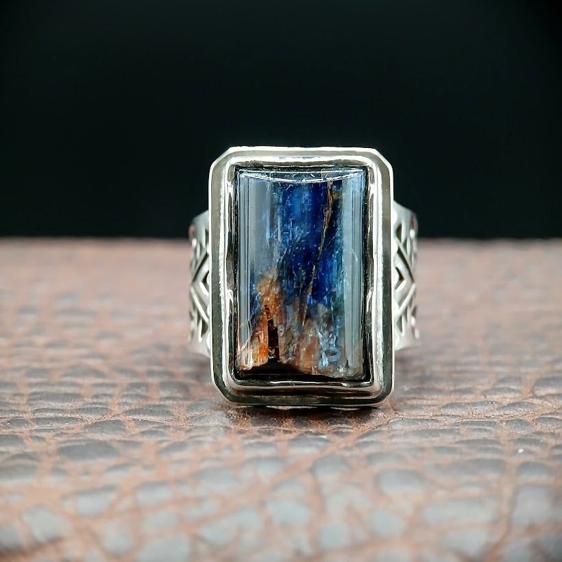 Silver ring with a rectangular blue stone on a textured surface