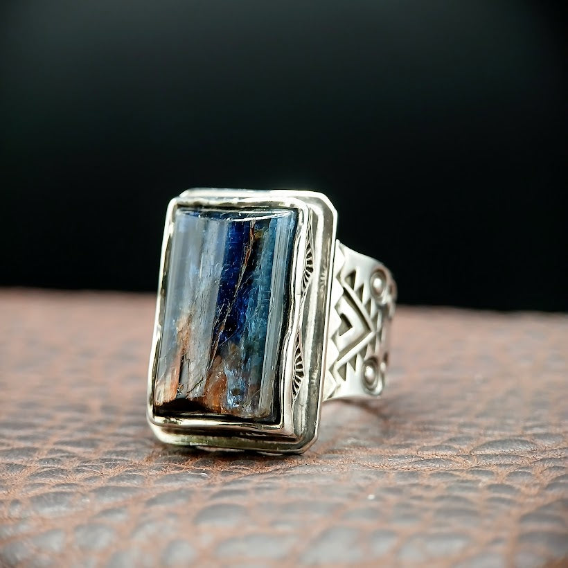 Silver ring with a rectangular blue stone on a textured surface