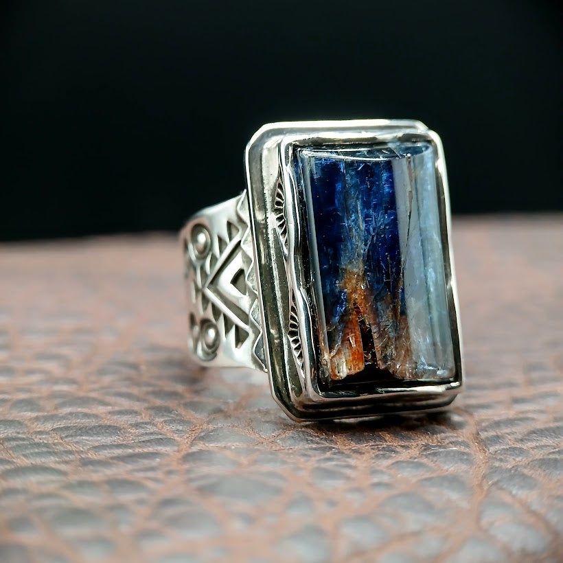 Silver ring with a rectangular blue stone on a textured surface