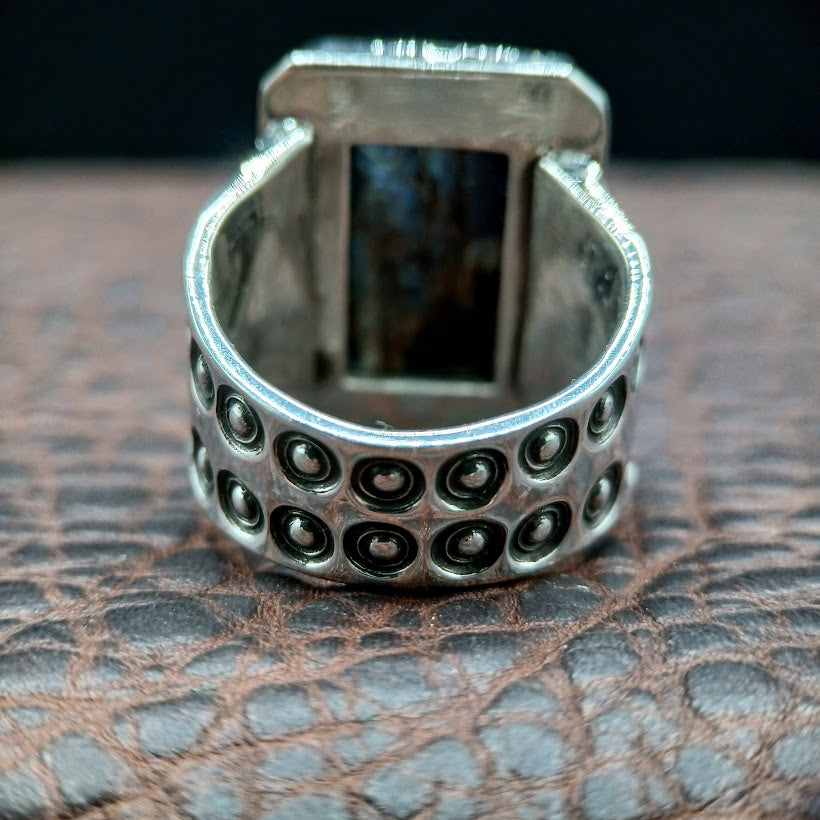 Silver ring with circular patterns on a textured surface
