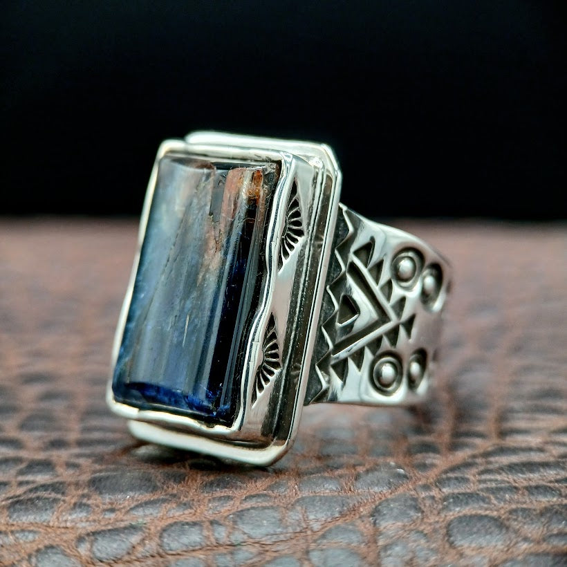 Silver ring with a blue gemstone on a brown leather surface