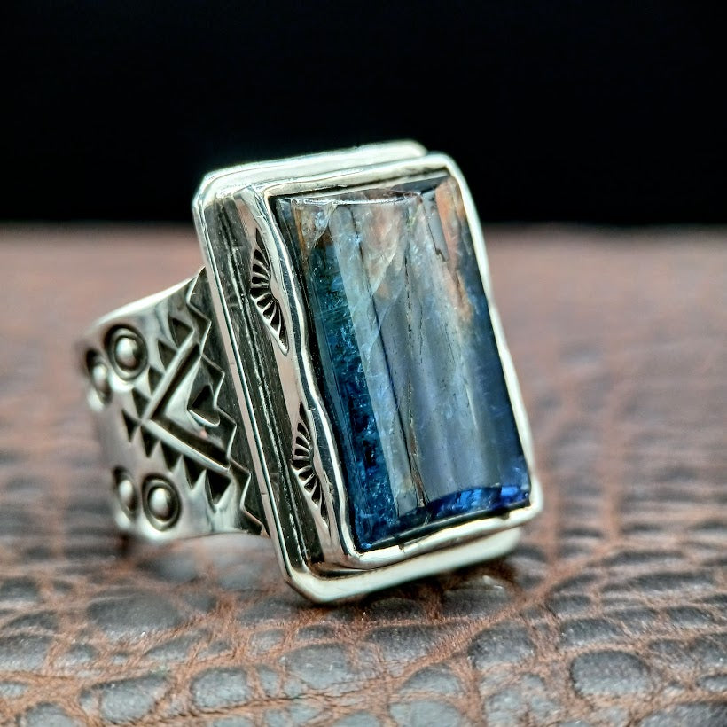 Silver ring with a rectangular blue stone on a textured surface