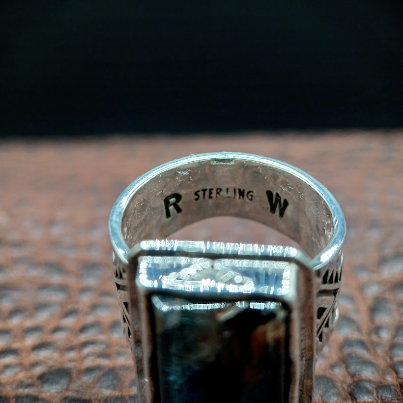 Silver ring with 'STERLING' engraving on a textured surface