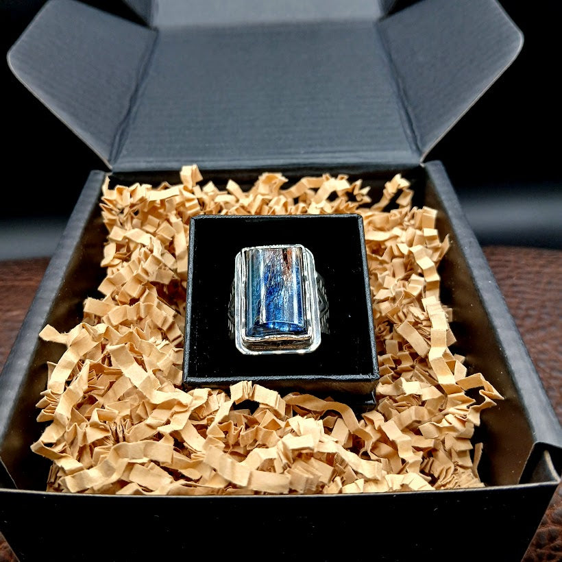 Ring with a blue gemstone in a black box with gold interior
