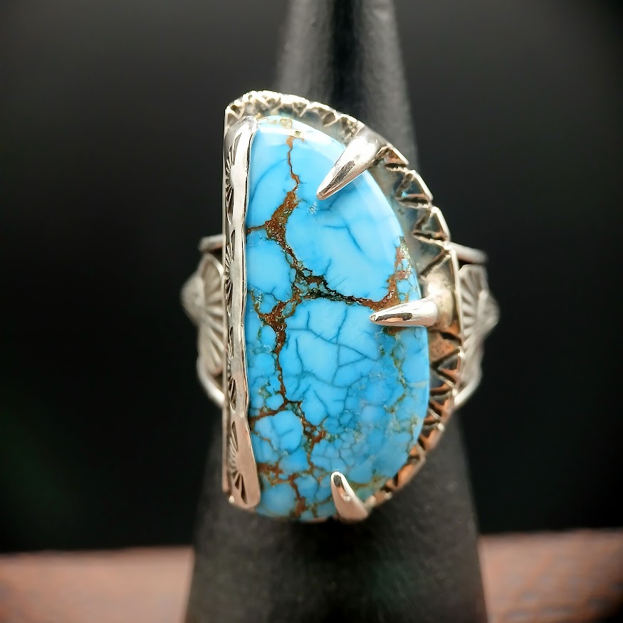 Turquoise ring with silver band on a black stand