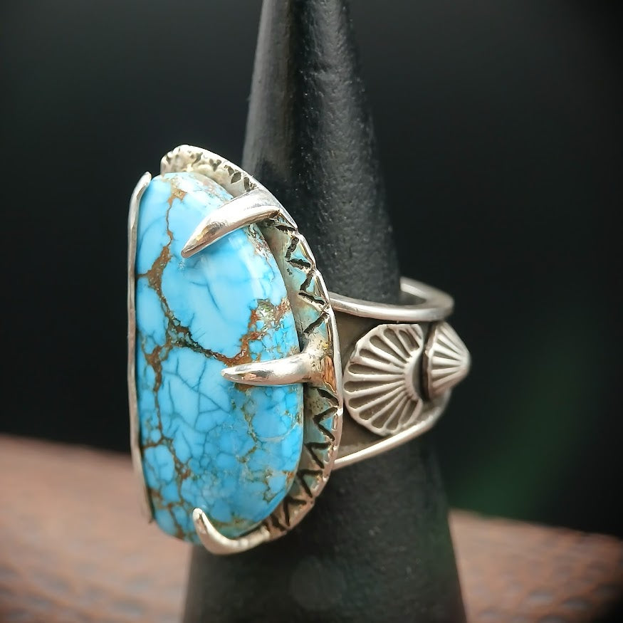 Turquoise ring with silver band on a black stand