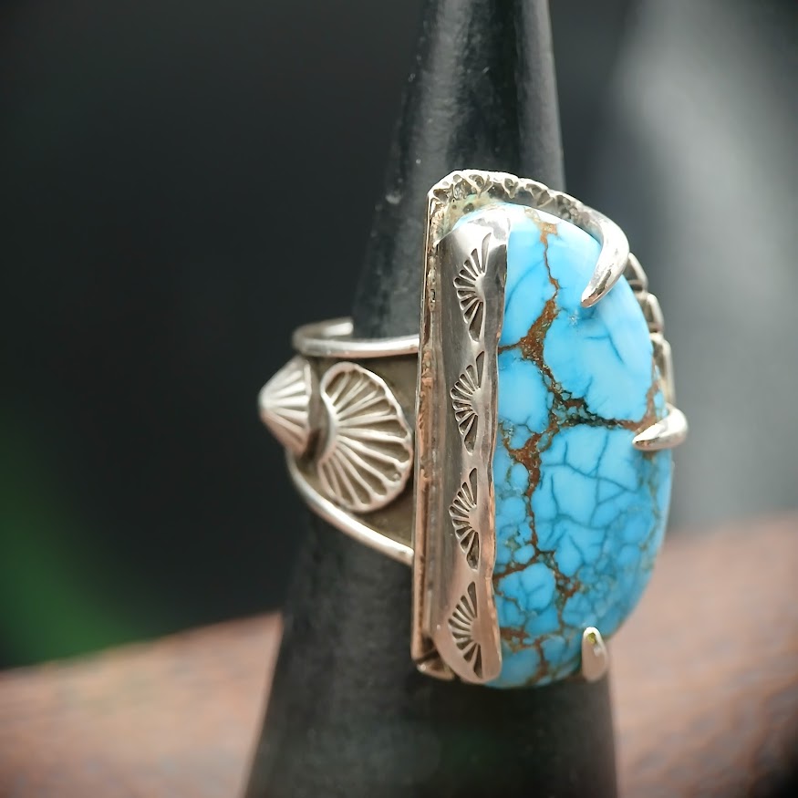 Turquoise ring with silver band on a black stand