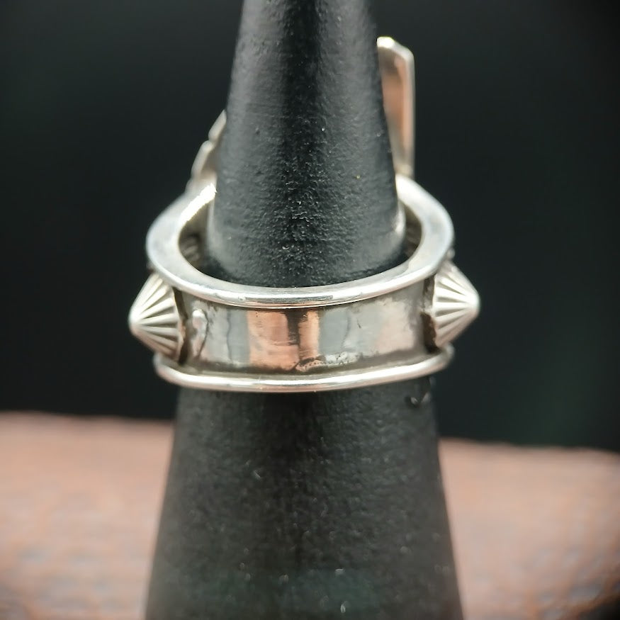 Band of Silver ring on a black stand with a dark background
