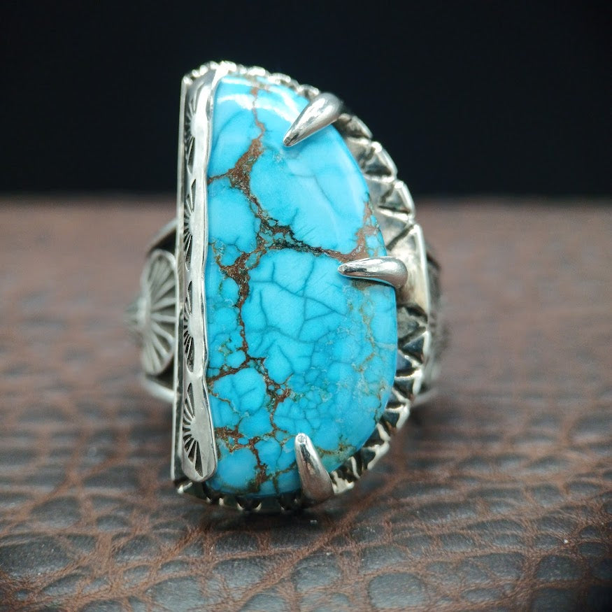 Turquoise ring with silver band on a textured surface