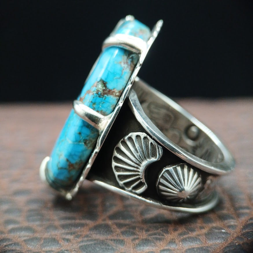 Silver ring with turquoise stone on a textured surface
