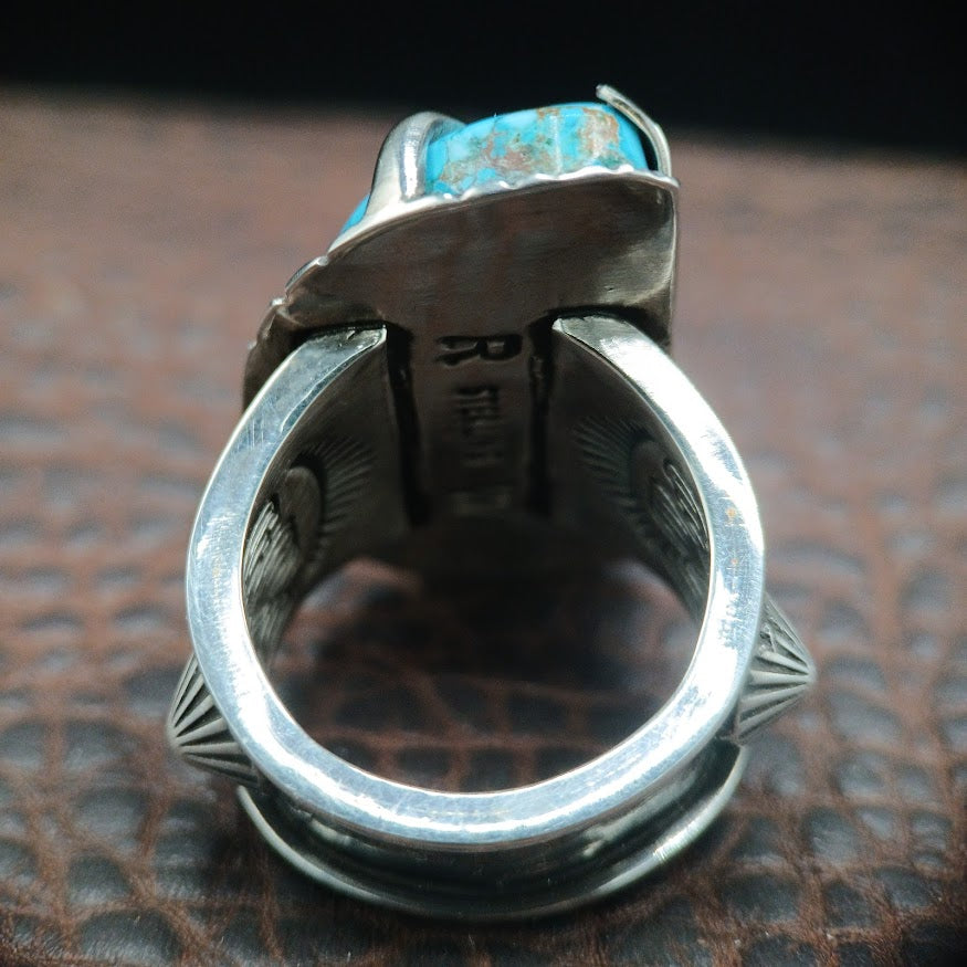 Silver ring with turquoise stone on a textured surface