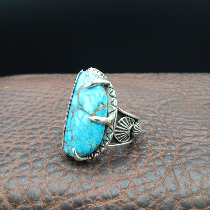 Silver and turquoise ring on dark brown leather