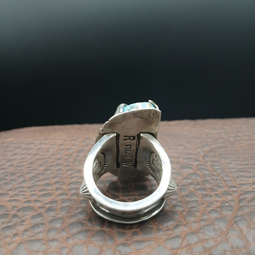 Silver ring with a textured design on a brown leather surface