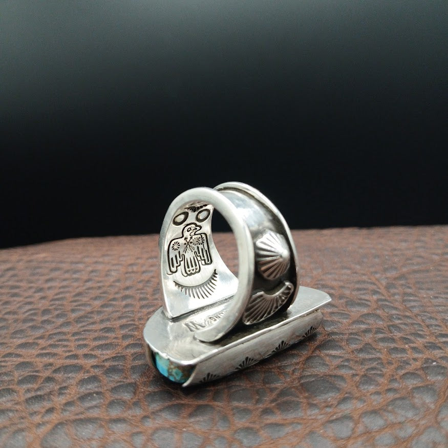 Silver ring with intricate design on a textured surface