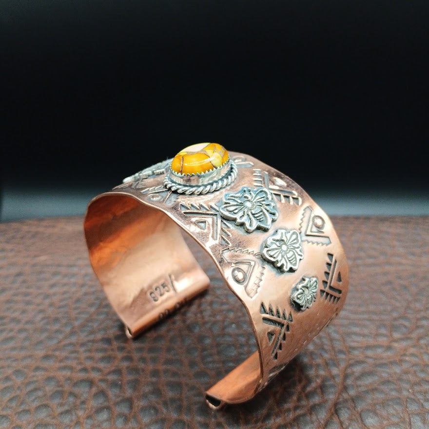 Copper bracelet with silver bee accents on a textured surface