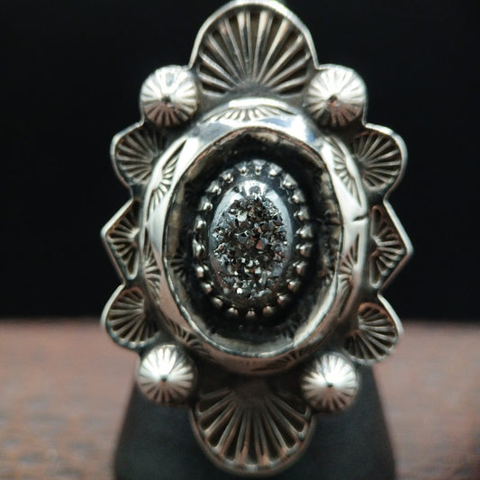 Silver ring with intricate design on a dark background