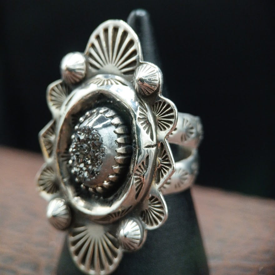 Silver ring with intricate design on a dark background