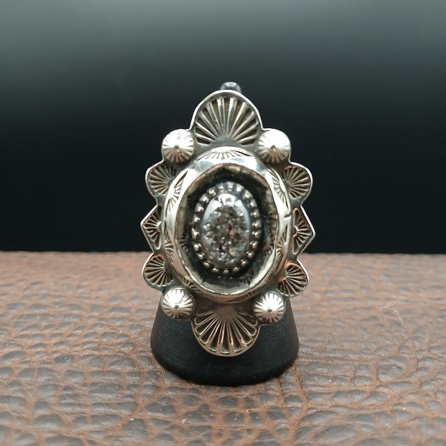 Silver ring with intricate design on a textured surface