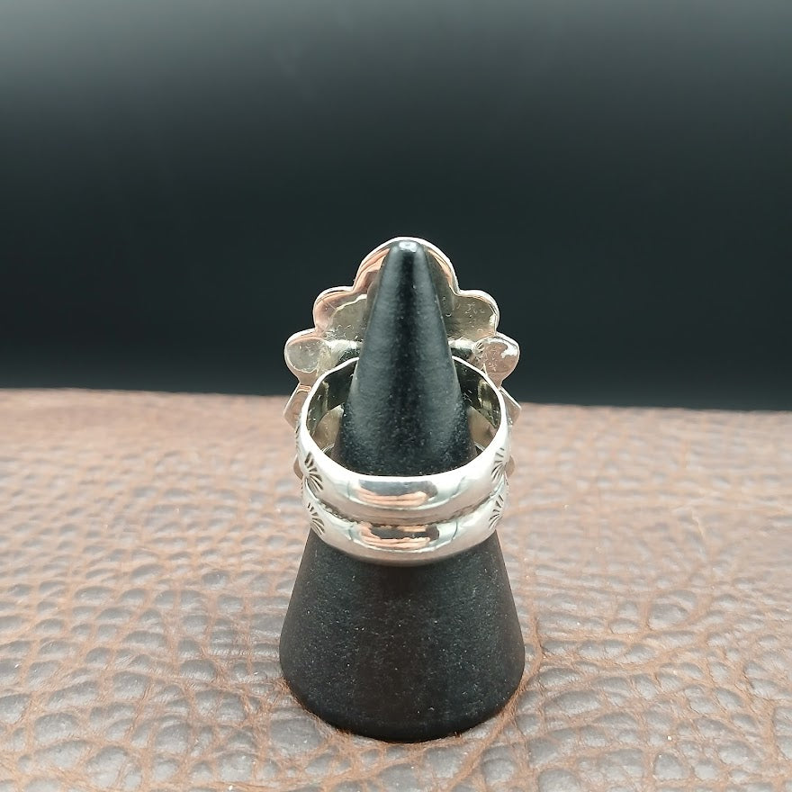 Silver ring on a black cone stands on a textured surface