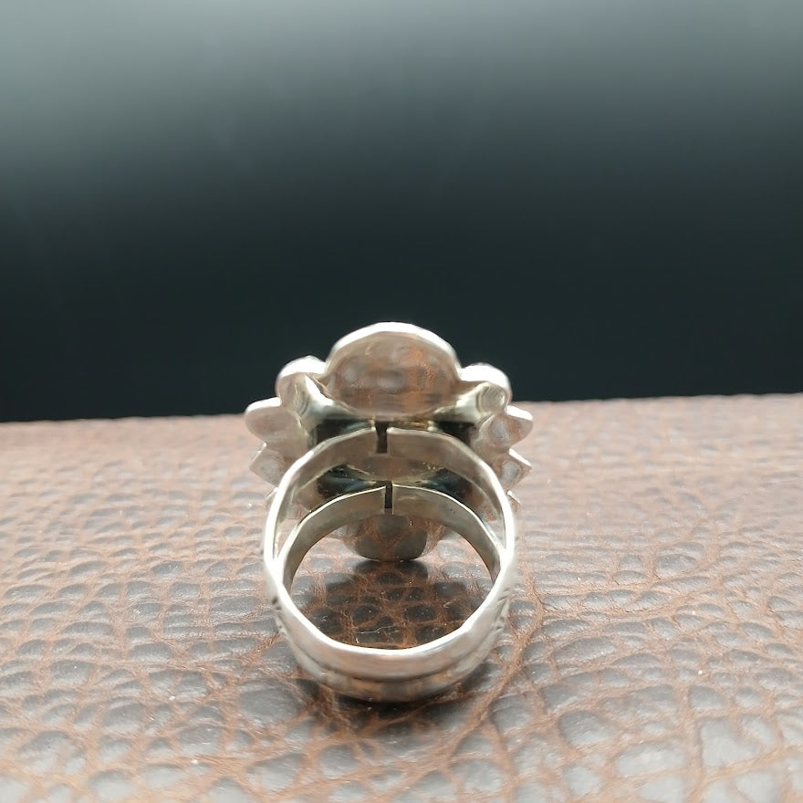Silver ring with intricate design on a textured surface
