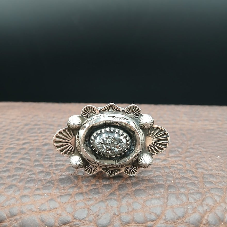 Silver ring with intricate design on a textured surface
