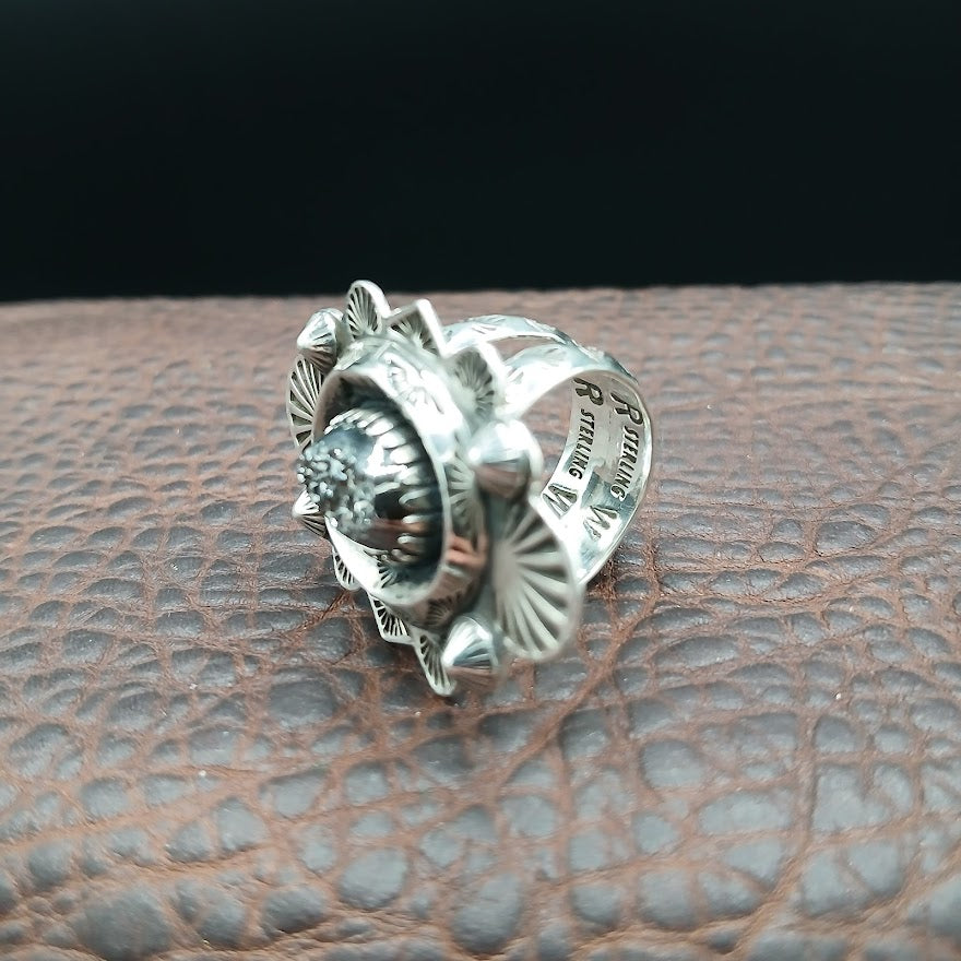 Silver ring with detailed design on a textured brown surface