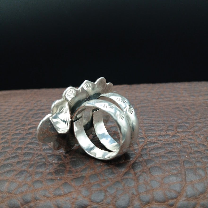 Silver ring with textured design on a brown leather surface