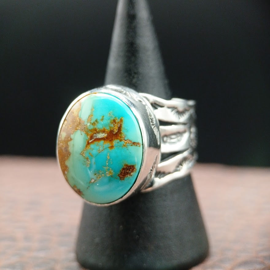Turquoise stone ring on a black stand with a dark background