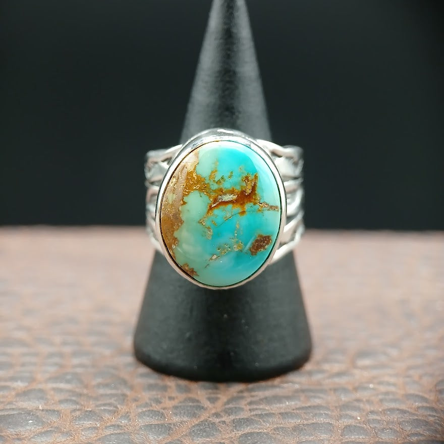 Turquoise stone ring on a black stand with a dark background
