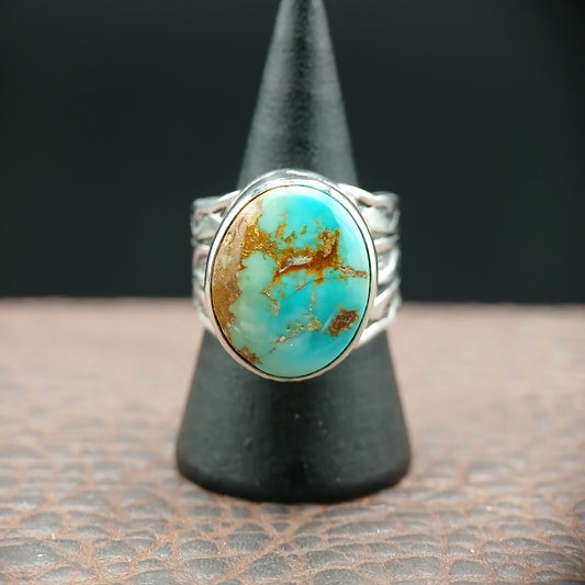 Turquoise stone ring on a black stand with a dark background