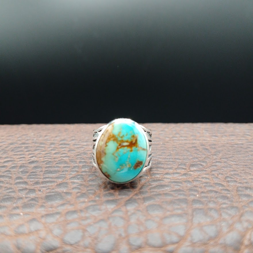Turquoise ring with silver band on a textured surface