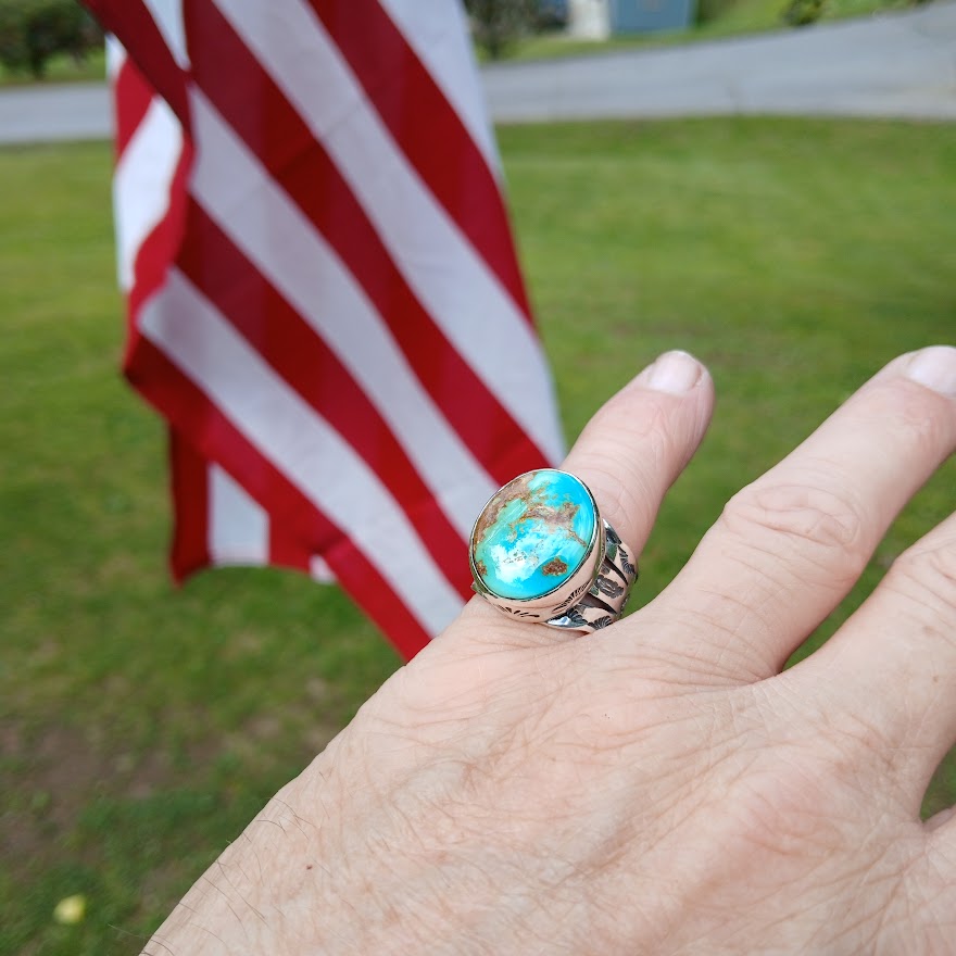 Turquoise ring on a hand with an American flag in the background