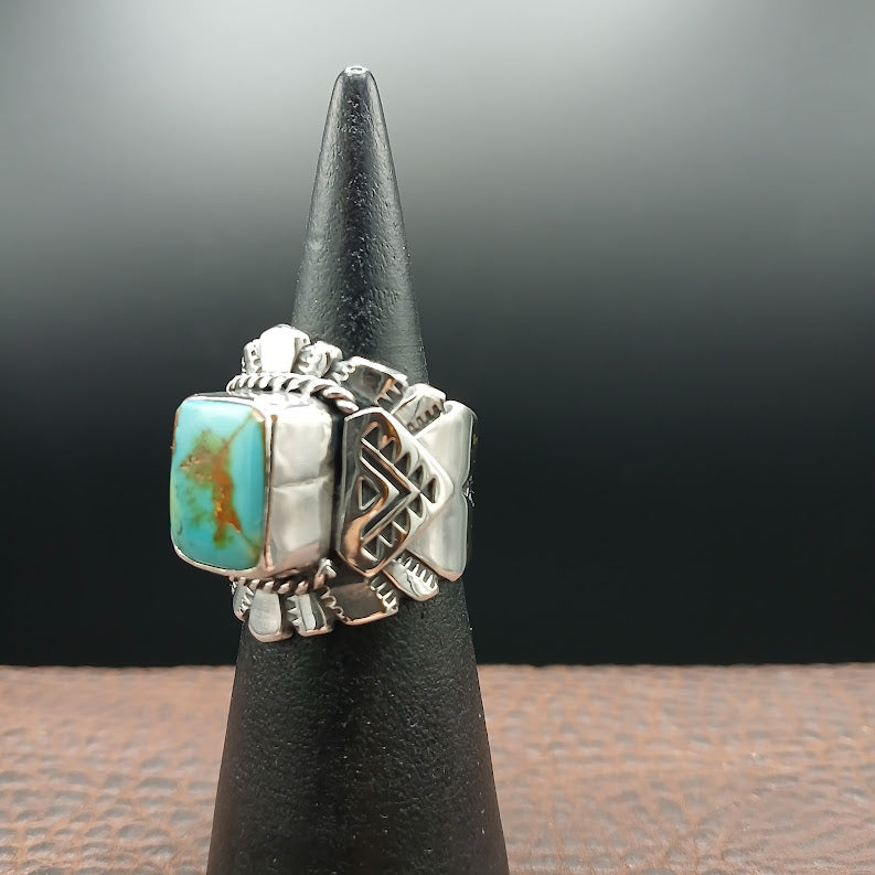 Silver ring with turquoise stone on a black stand against a dark background