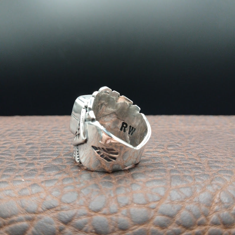 Silver ring with engraved design on a textured surface