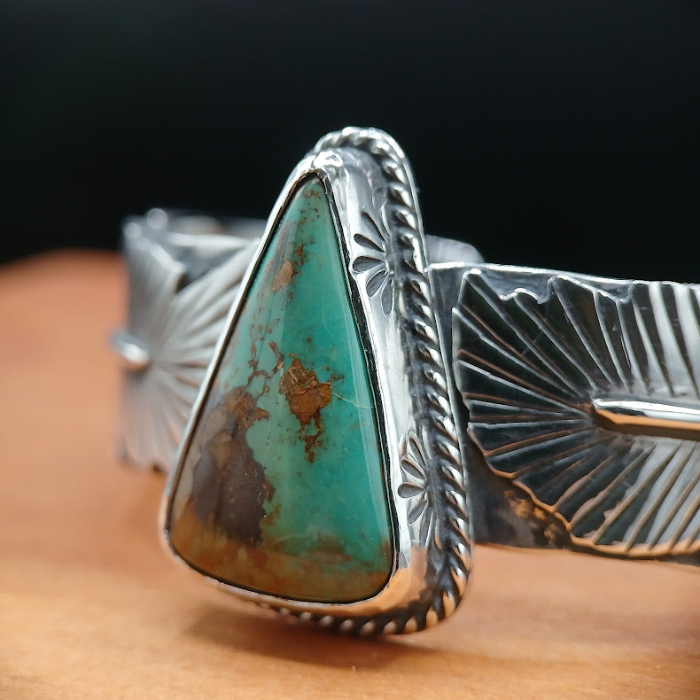 Silver bracelet with a large turquoise stone on a wooden surface